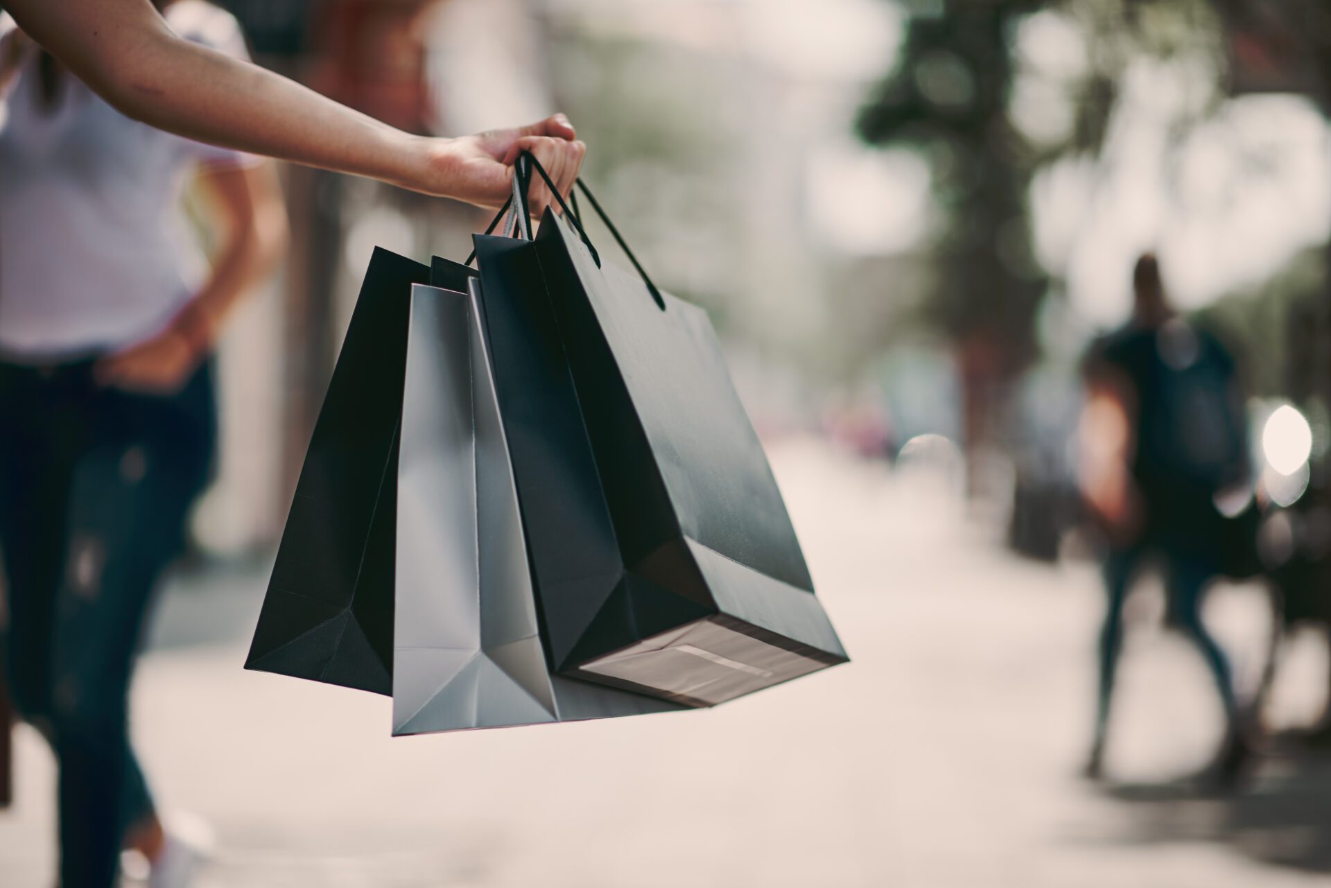Close up of woman`s hand holding shopping bags while walking on